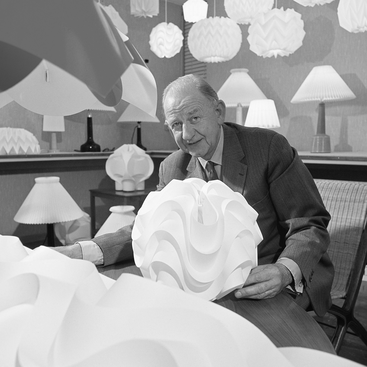 Sort/hvid billede af Jan Klint på sit kontor i blandt smukke design lamper fra Le Klint